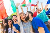 113434127-italian-supporters-celebrating-at-stadium-with-flags-couple-kissing-in-the-crowd-of-fans-watching-a.jpg