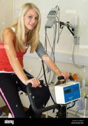 junge-frau-tragt-einen-ergometer-test-in-der-medizinischen-praxis-junge-frau-auf-einem-ergometer-in-der-chirurgie-junge-frau-fuhrt-einen-ergometer-tes-jgmead.jpg